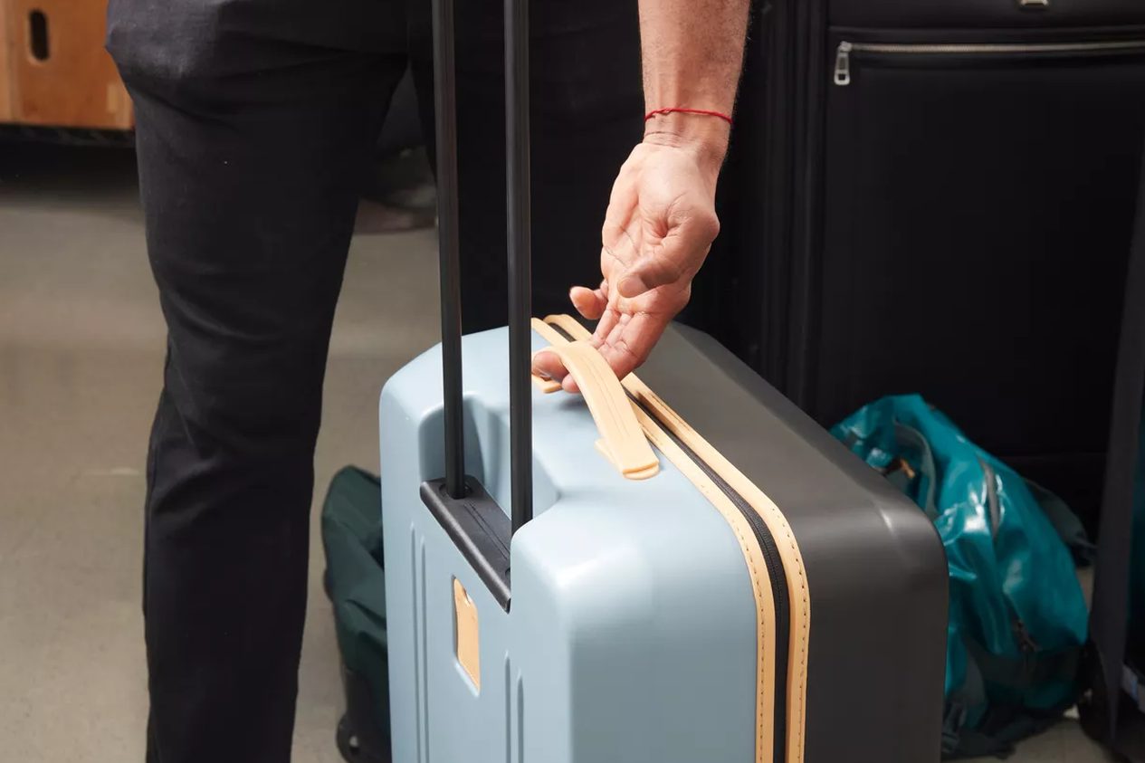 five carry-on suitcases lined up on a hardwood floor, handles extended, shot from a low angle