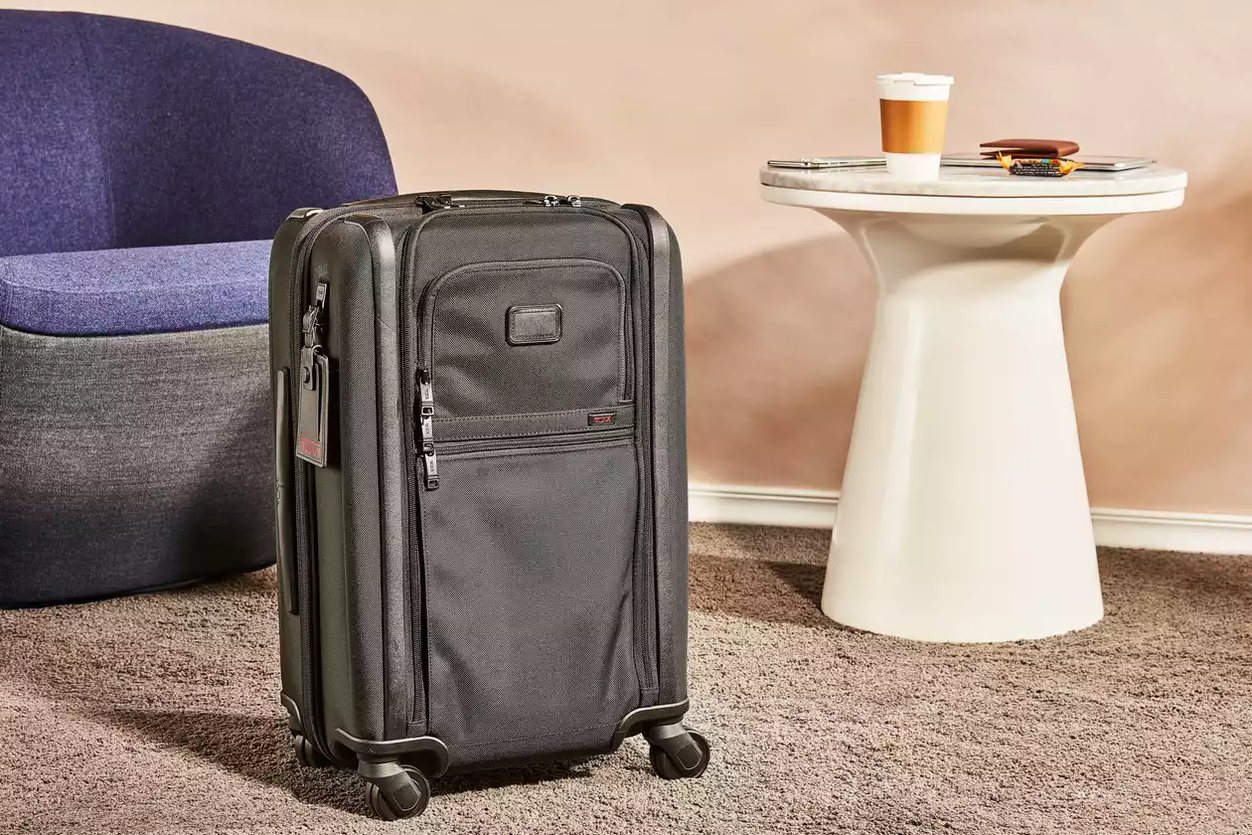 five carry-on bags lined up side by side on a hardwood floor