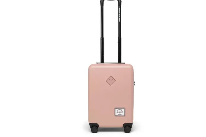 hard-shell carry-on open on a hotel bed, packed