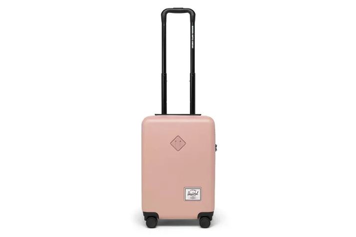 hard-shell carry-on open on a hotel bed, packed