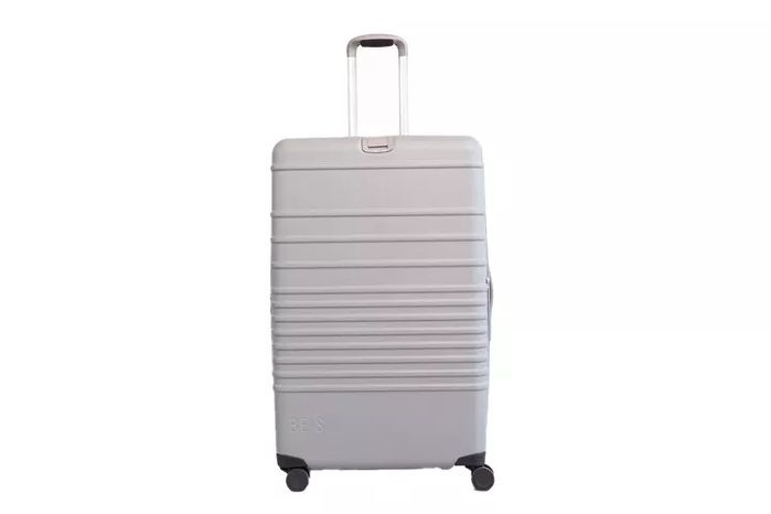 ZDX Large Expandable standing next to a check-in counter, handle extended