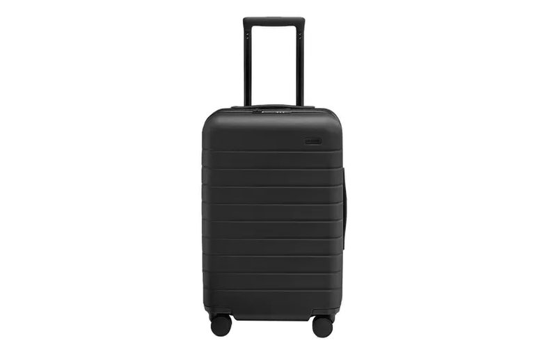 hard-shell carry-on open on a hotel bed, packed