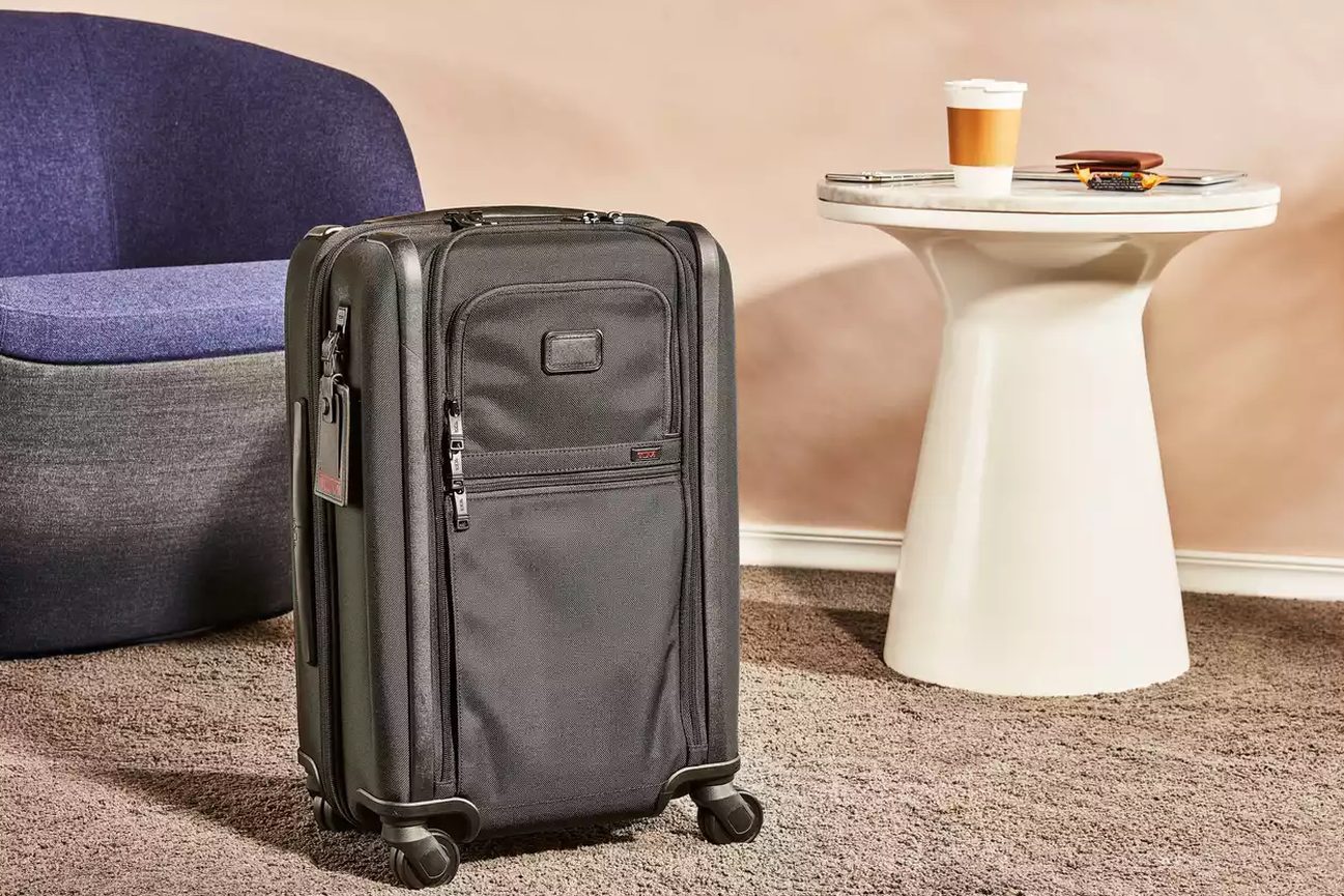 Essential Cabin packed open on a hotel bed, shoes tucked into the compression pad
